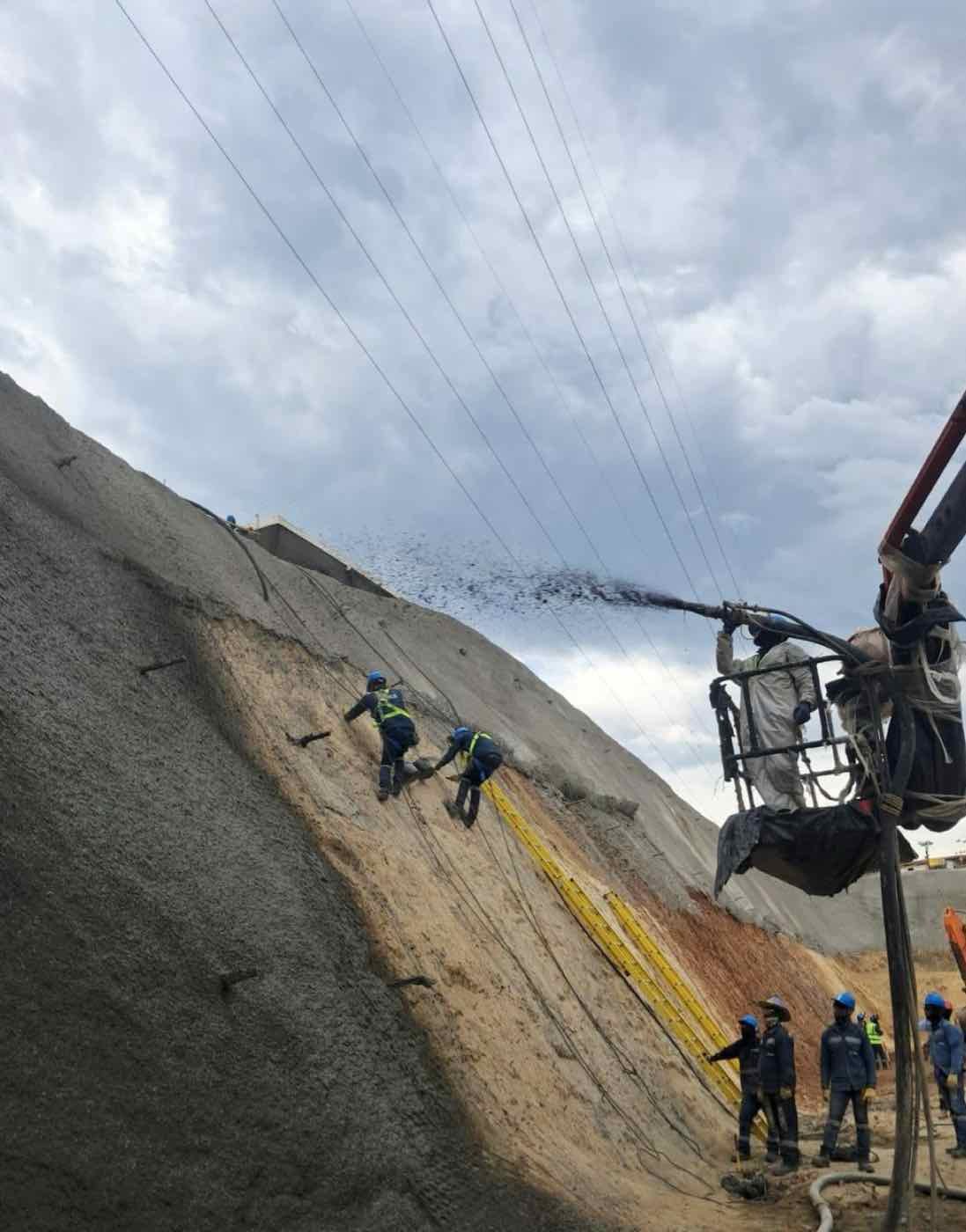 Operarios instalando anclajes en un talud con canastilla de perforación
