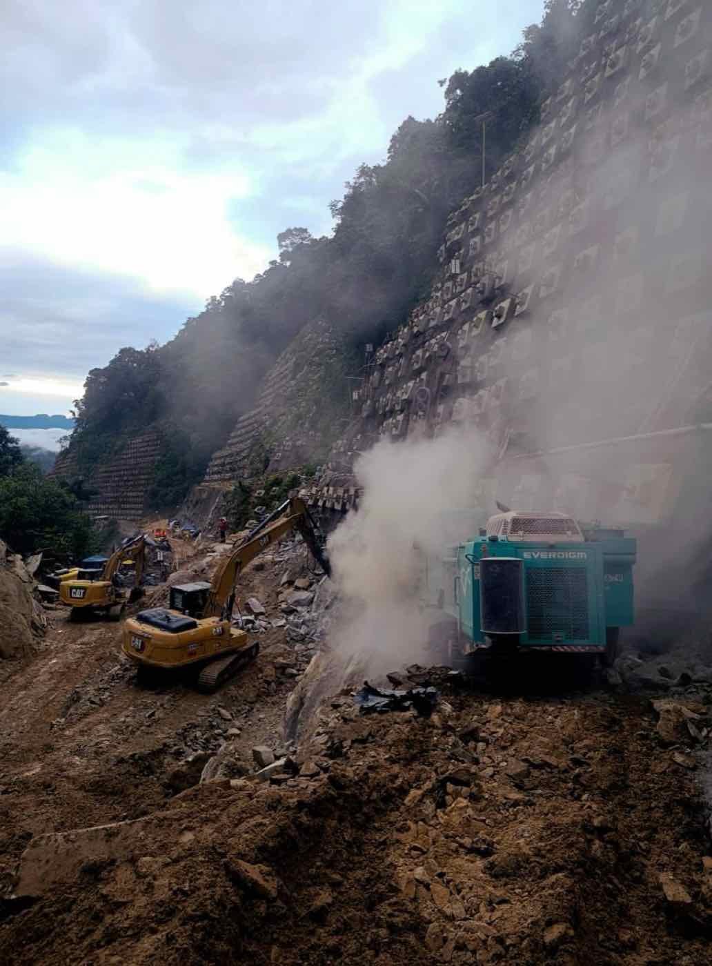 Equipo de perforación trabajando en un talud con polvo de roca